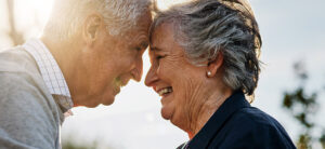 Älteres Ehepaar lächelt sich liebevoll an. Gemeinsame Erinnerungen trotz Demenz lebendig halten.
